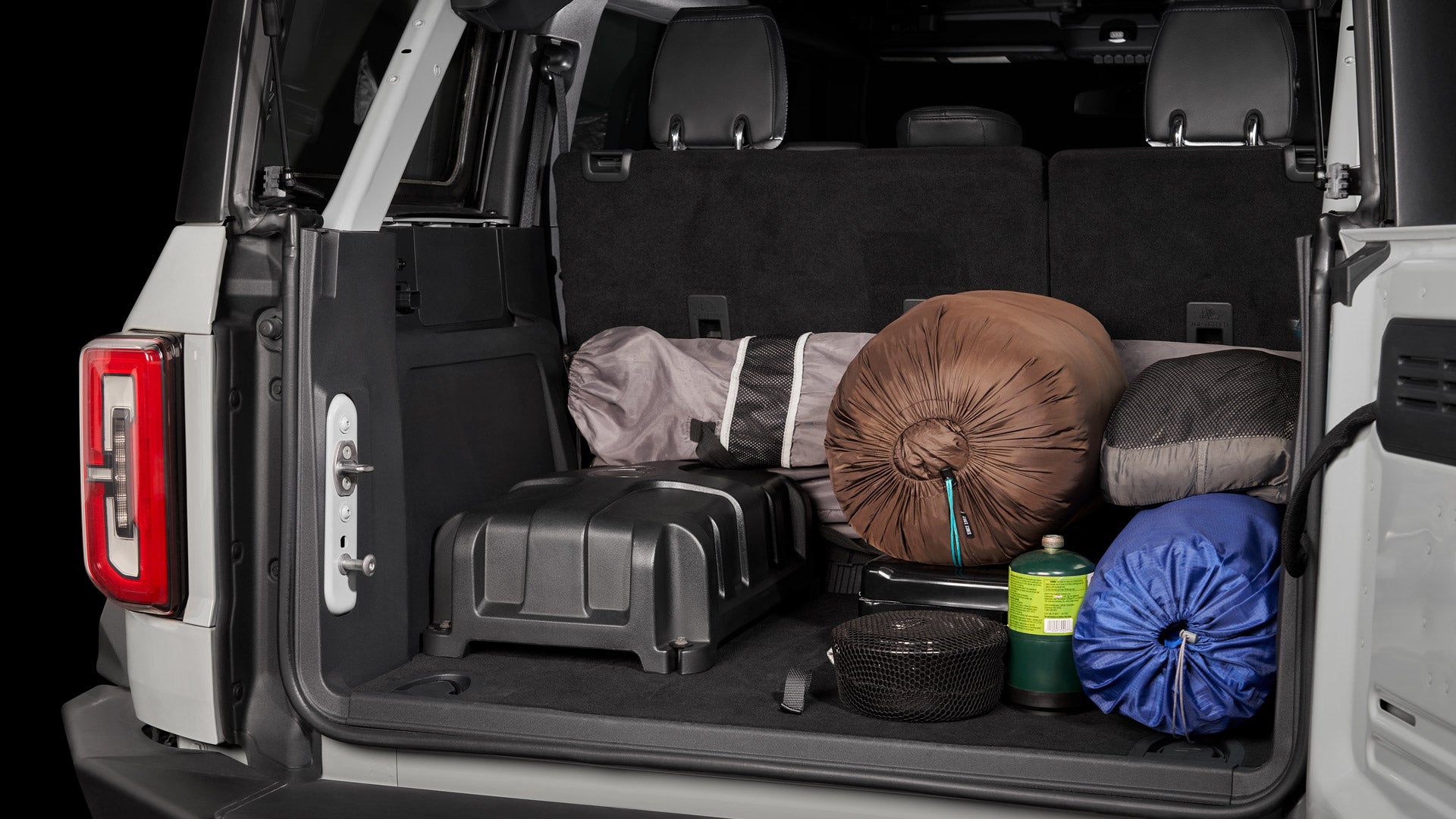 StowAway enclosure installed in the back of an SUV, surrounded by camping gear