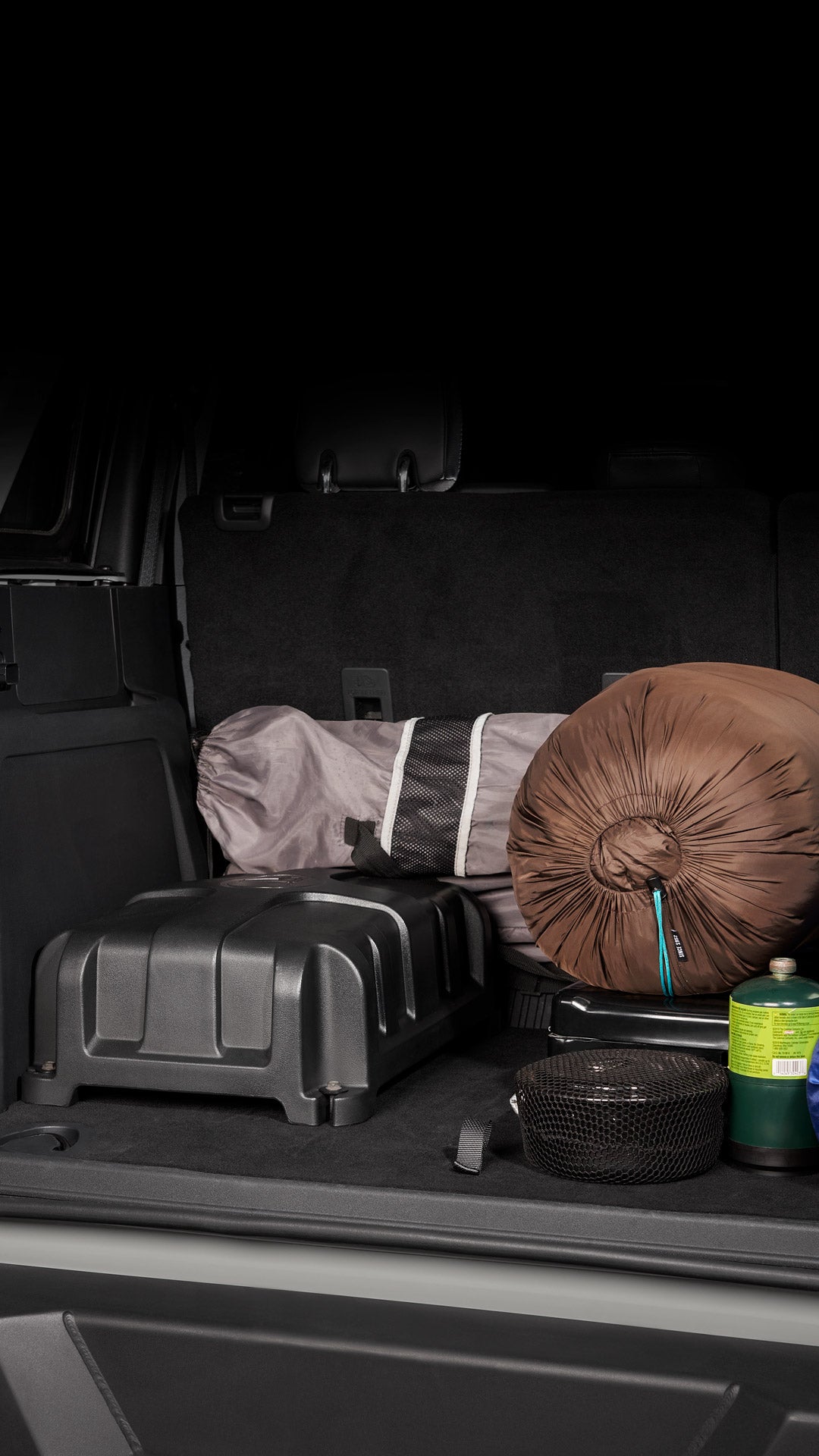 StowAway enclosure installed in the back of an SUV, surrounded by camping gear